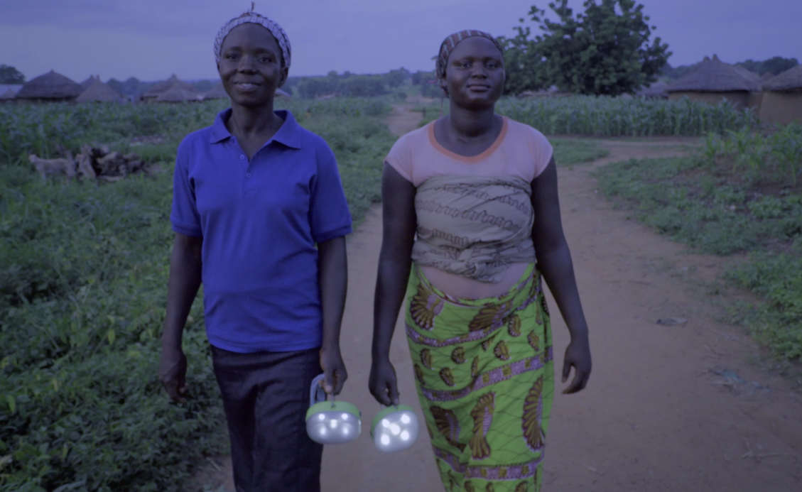 Two Ghanaian women carry torches in the dark