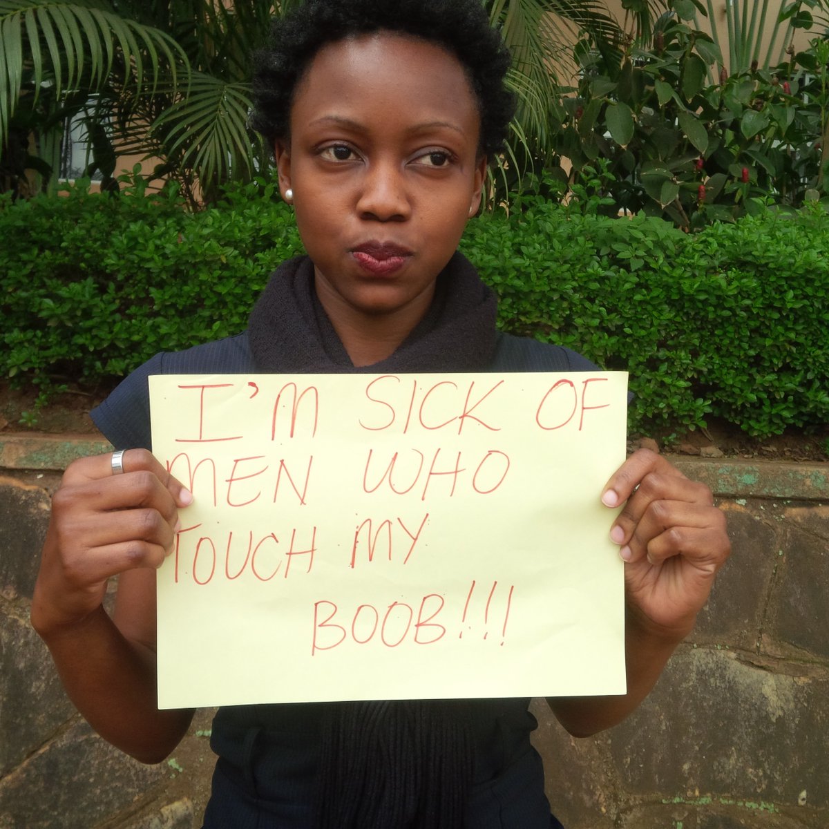 Activist with a sign reading "I'm sick of men touching my boobs" 