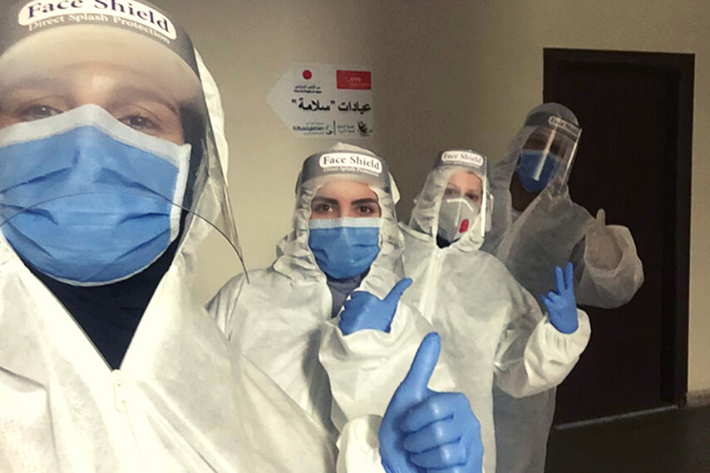 Healthcare workers in PPE giving a thumbs up