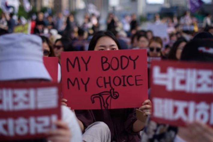 a woman holds a sign saying my body, my choice