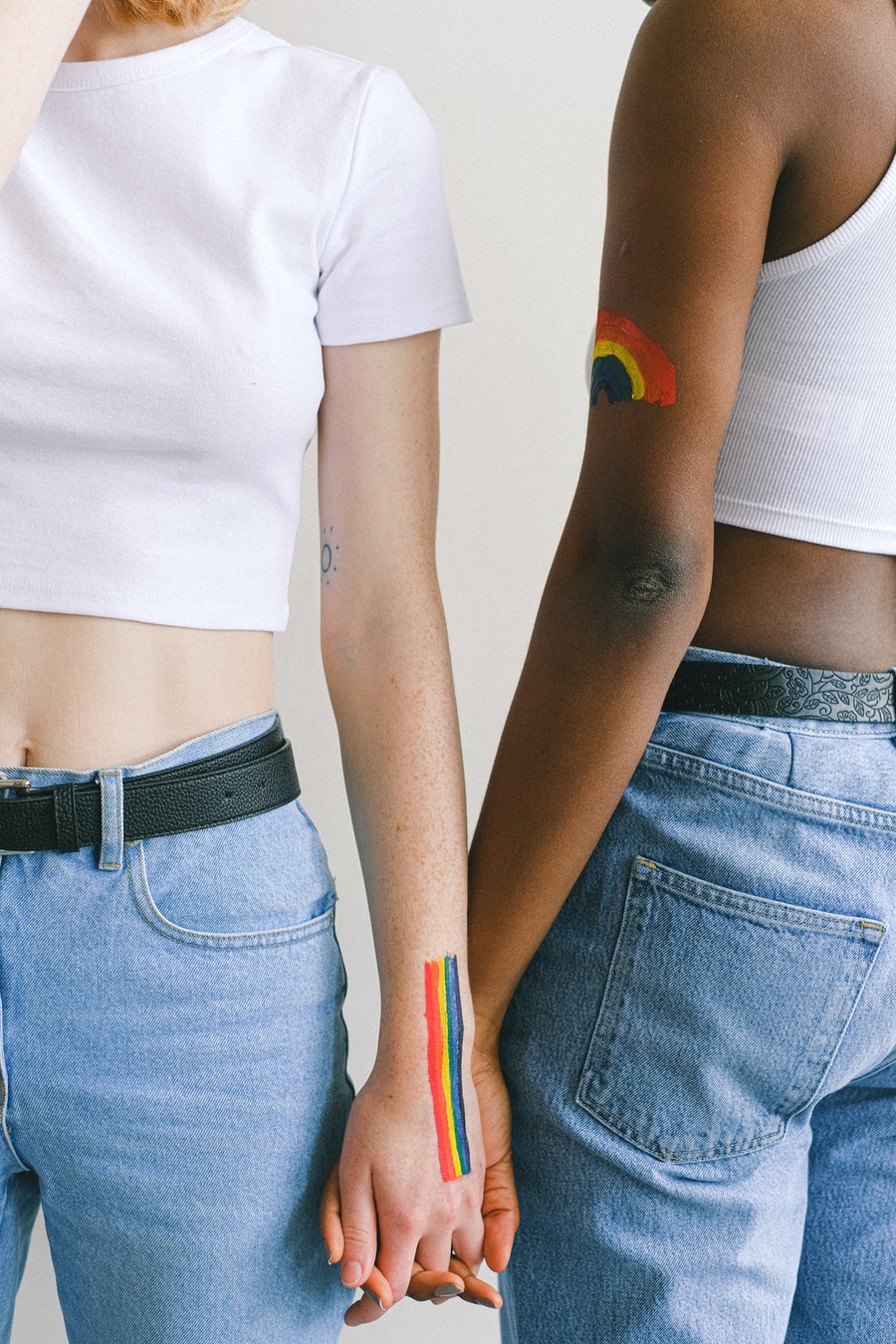 Two women holding hands, one with a Pride flag painted on