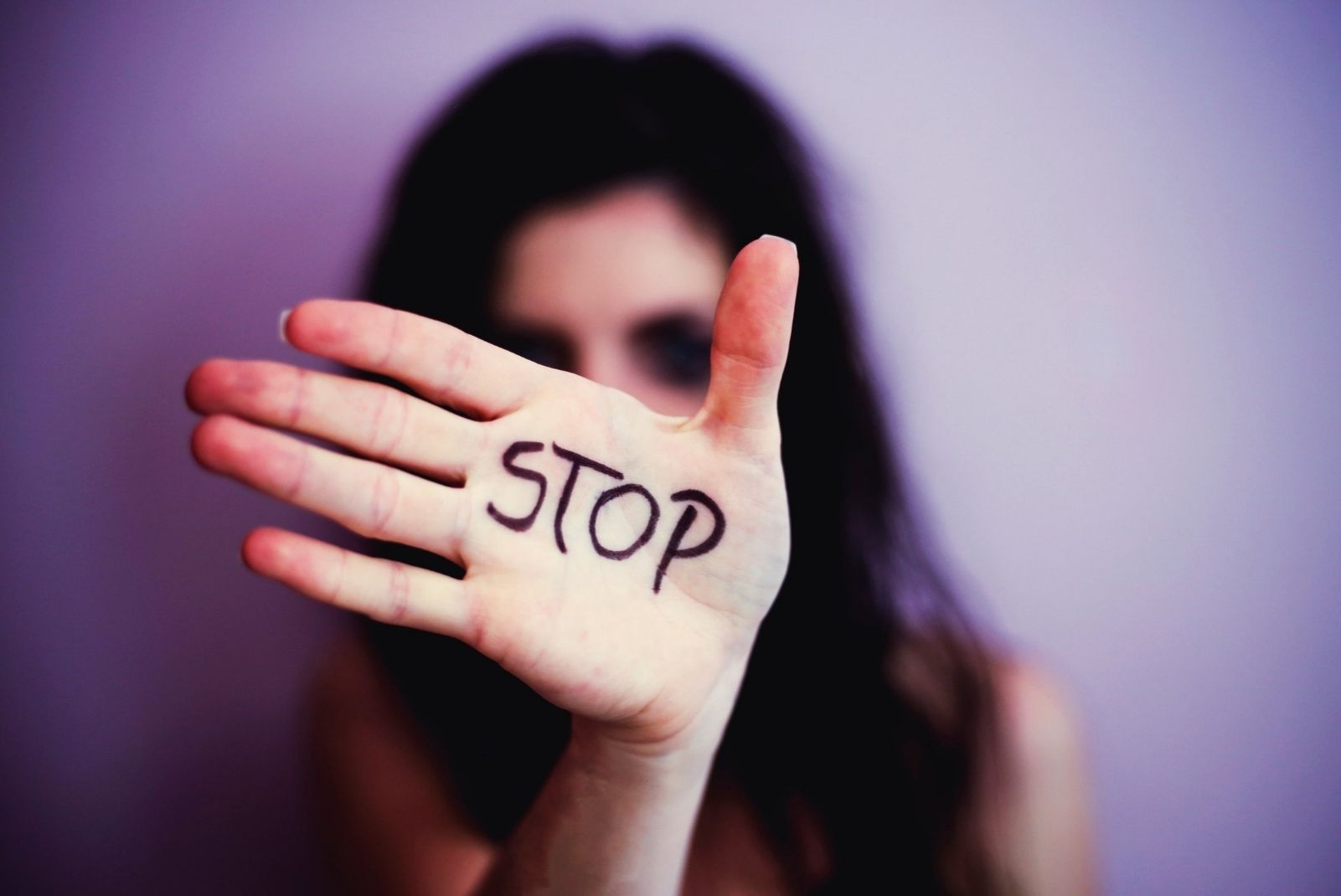 A woman with her hand in front of her face. Written on her hand is "STOP"