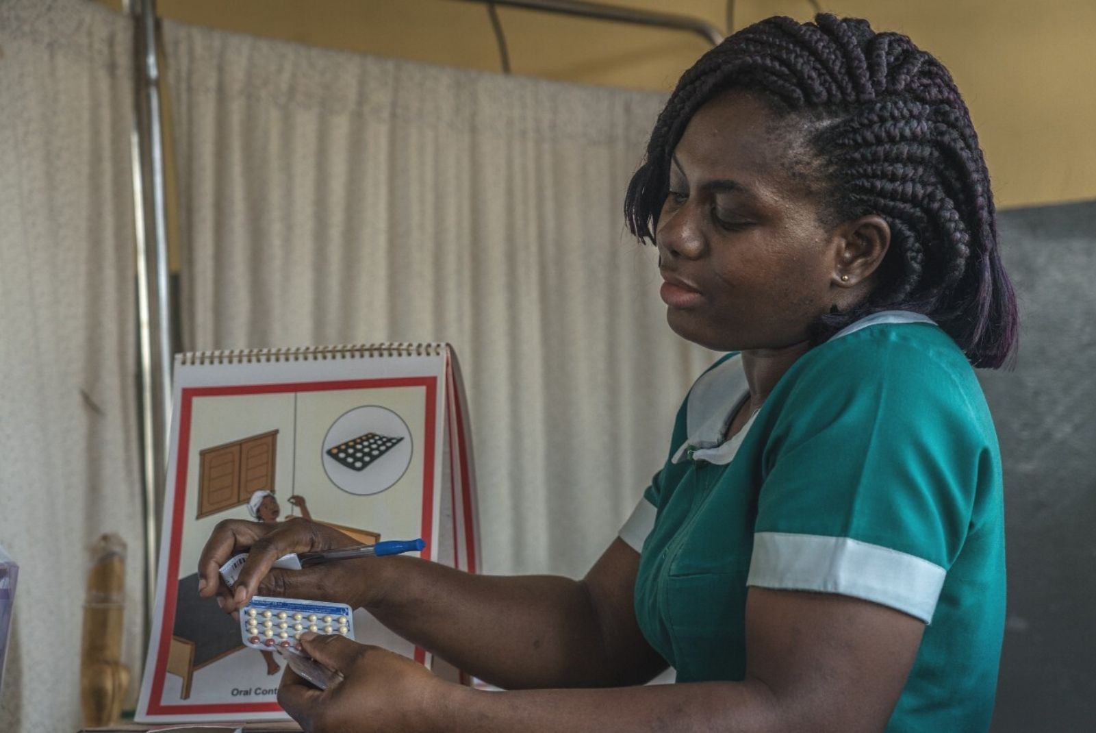 A healthcare worker in Ghana shows a client the Pill