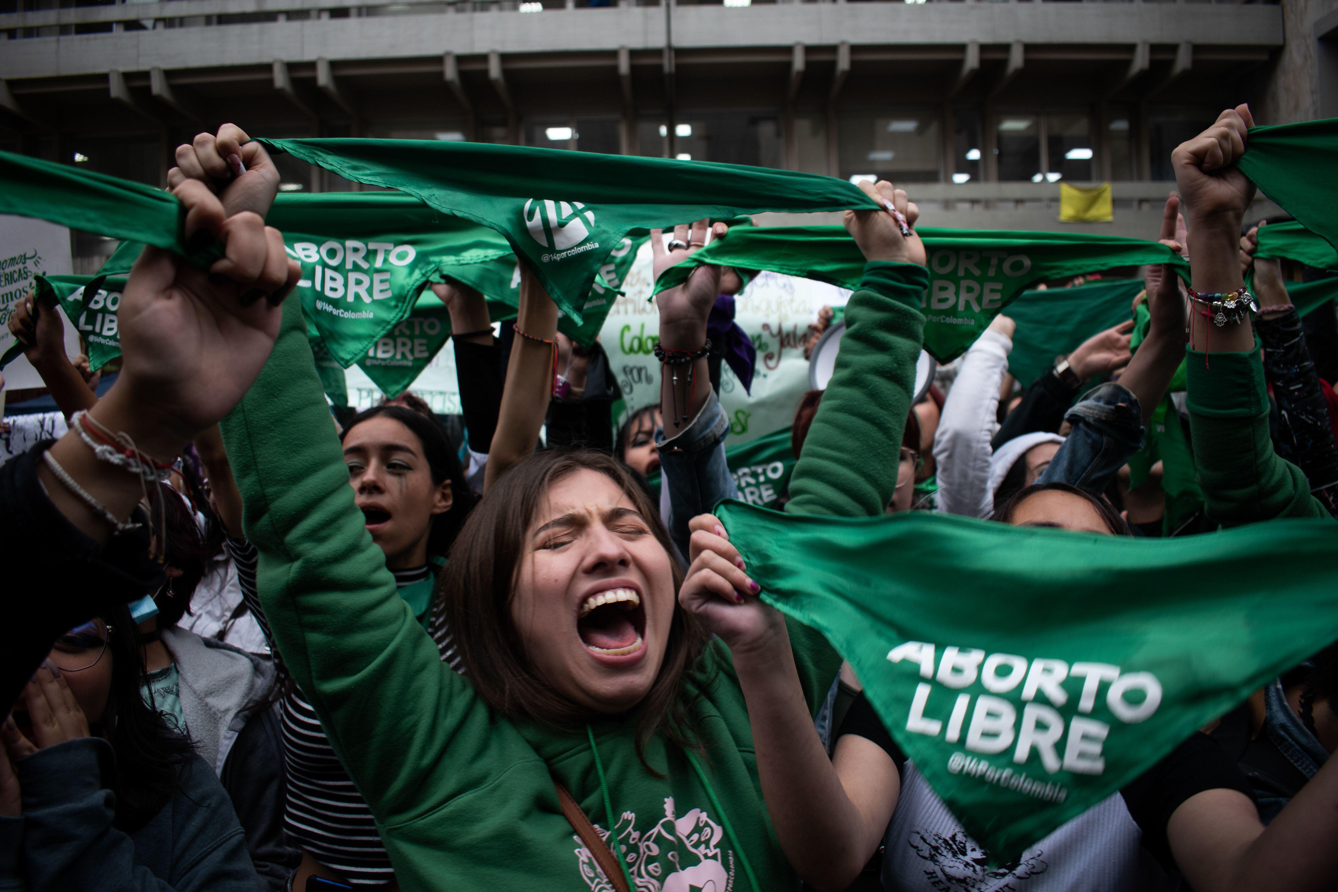 Woman outside the Colombian constitutional with eyes closed holding a sign saying liberalize abortion