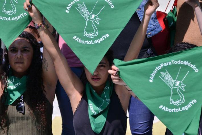 Woman waving a green flag in support of abortion care 