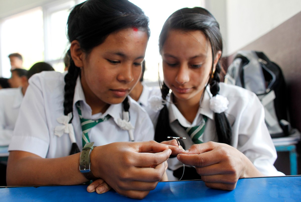 Two young people holding an IUD