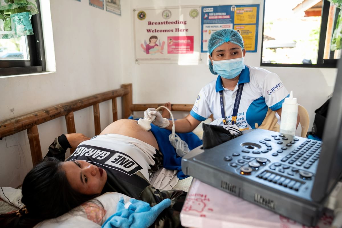 A pregnant woman is given an ultrasound by a health worker at a makeshift clinic