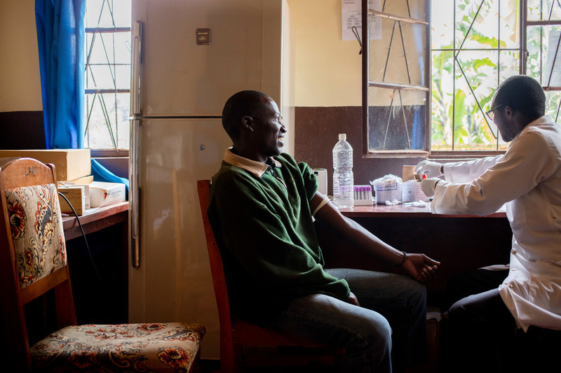 Justin, 41, sits for a blood test by lab specialist Maurice, 33, at ABUBEF's clinic in Ngozi. Due to budget cuts Maurice now works part time; he also works at the local public hospital. Lost funds also mean less reagents available for his equipment making some tests impossible to continue. 