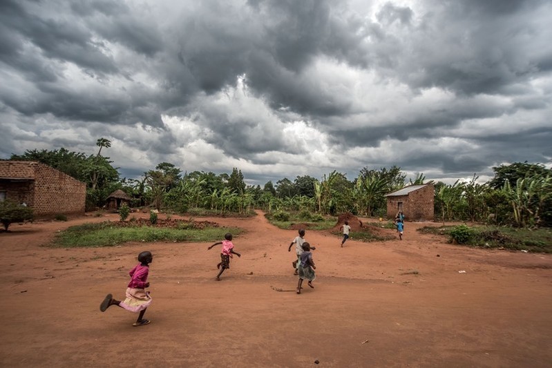 Children run through a village in Kasawo, Uganda, as a storm approaches.