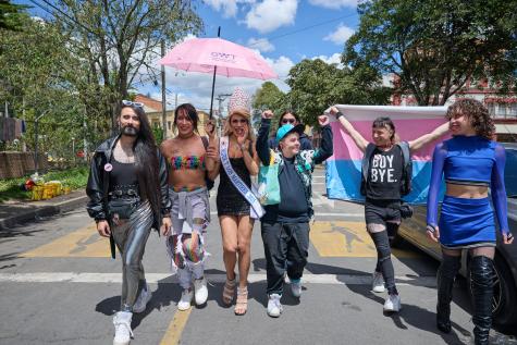 Members of the LGBTQI+ community walk towards the camera in Colombia. They are happy and holding their hands in the air. 