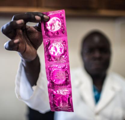 A health practitioner holds up condoms in Gulu clinic, Uganda