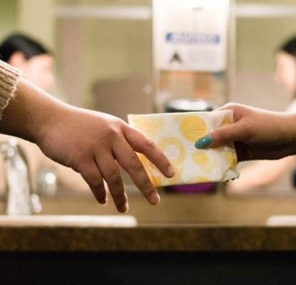 One hand passes a sanitary pad to another