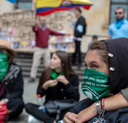 Abortion rights protestor with green scarf over her face