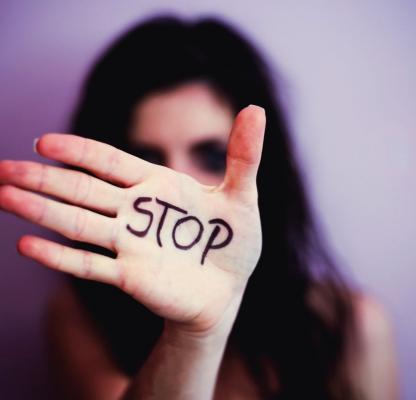 A woman with her hand in front of her face. Written on her hand is "STOP"