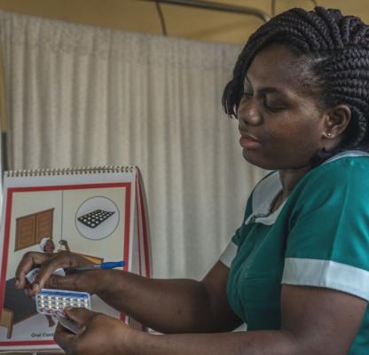 A healthcare worker in Ghana shows a client the Pill