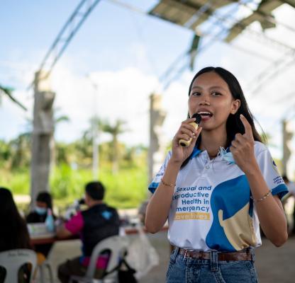 Youth Volunteer Charlaine Mae Leones speaks during a post-Typhoon Opong reproductive health medical mission at a damaged covered court in Masbate province,