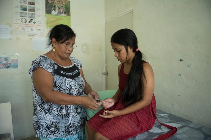 woman with young woman handing contraception