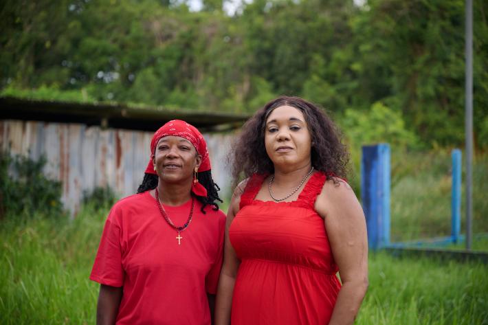 Two women in red face the camera in suriname looking proud. 