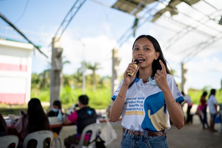 Youth Volunteer Charlaine Mae Leones speaks during a post-Typhoon Opong reproductive health medical mission at a damaged covered court in Masbate province,