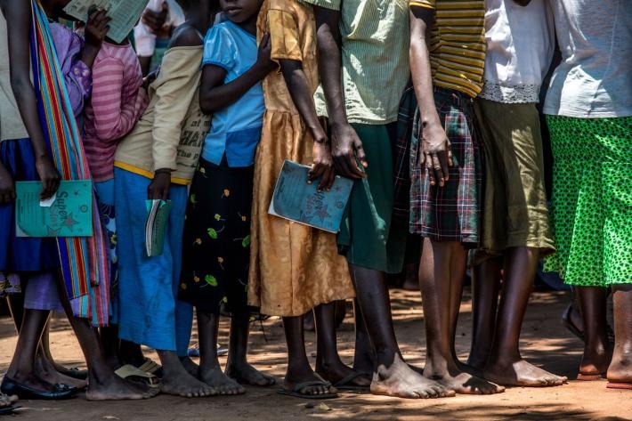 Exercise books in hand, young girls queue up for the HPV vaccine. 