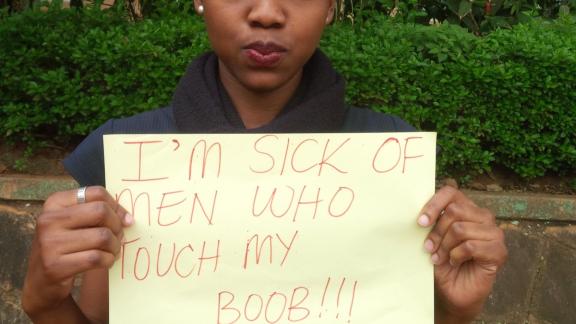 Activist with a sign reading "I'm sick of men touching my boobs" 