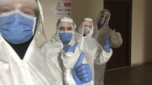 Our colleagues in Lebanon - healthcare workers wearing full PPE taking a selfie with their thumbs up