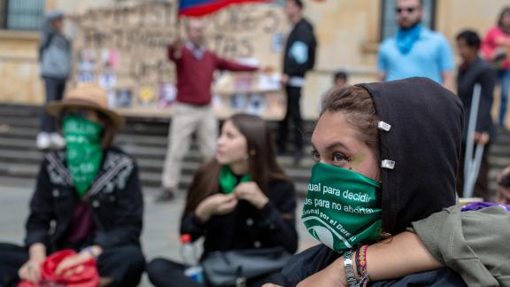 Abortion rights protestor with green scarf over her face