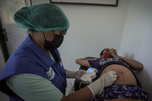 A healthcare professional scans a pregnant person in the aftermath of Tropical Cyclone Seroja in Indonesia